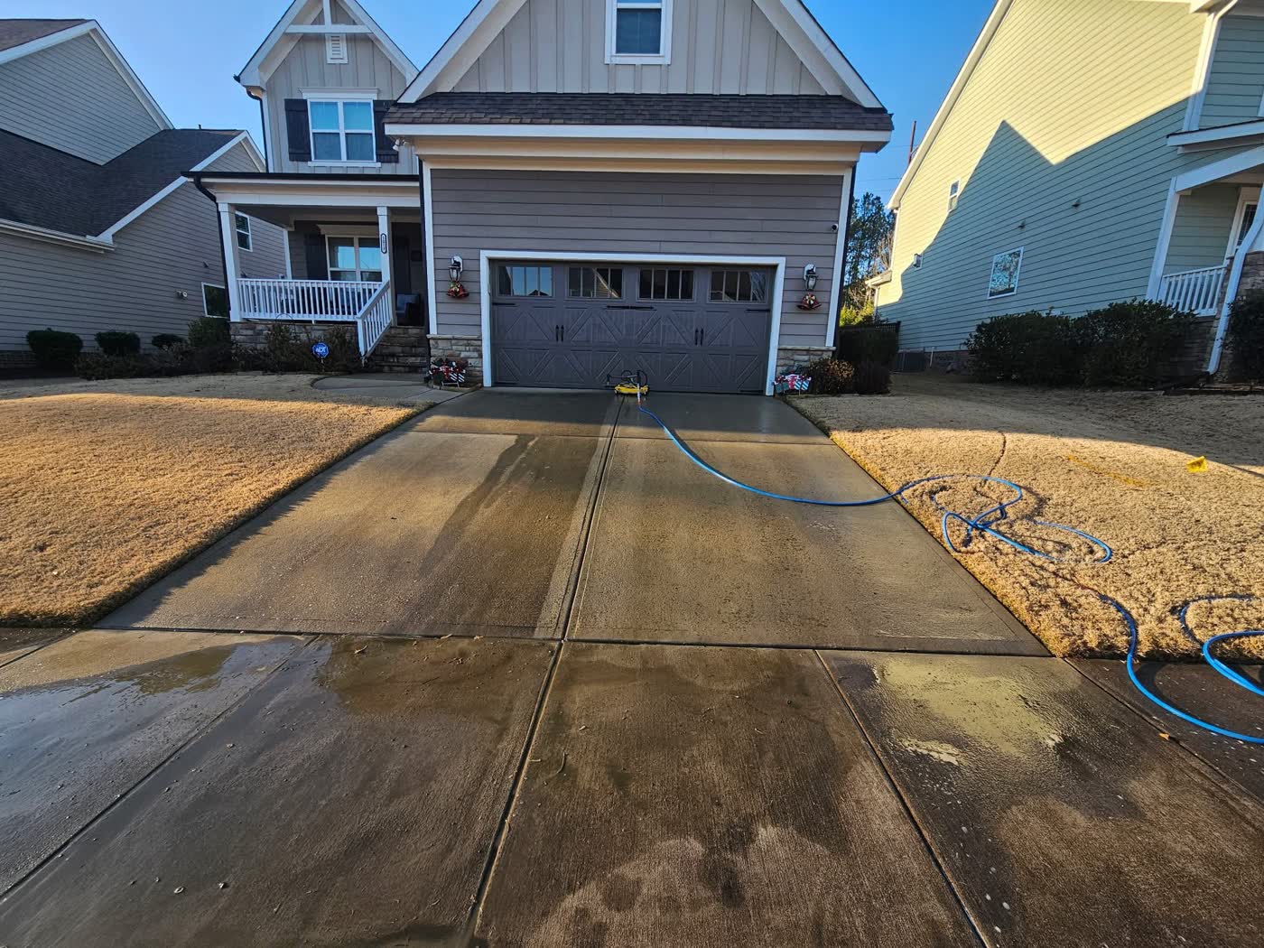 Surface cleaner cutting a bright, clean path across a gray concrete driveway