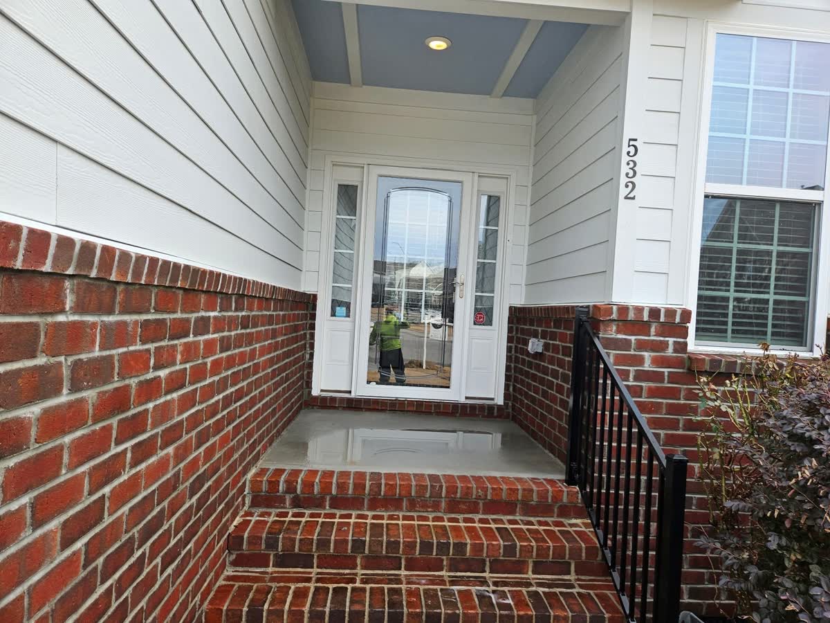 Wet, freshly washed brick porch and light siding at a home entrance